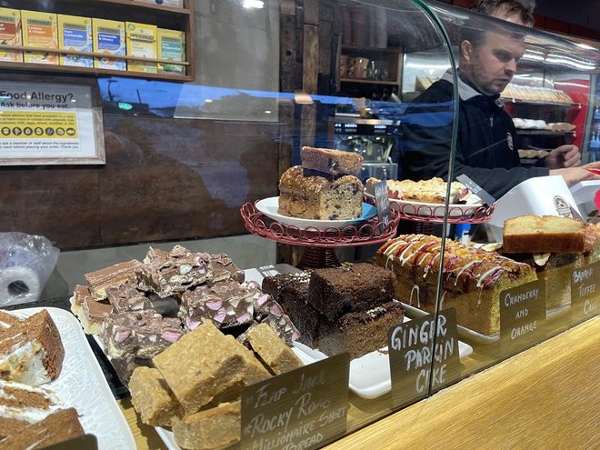 Brownies, flapjacks and loaf cake on stands behind the counter glass