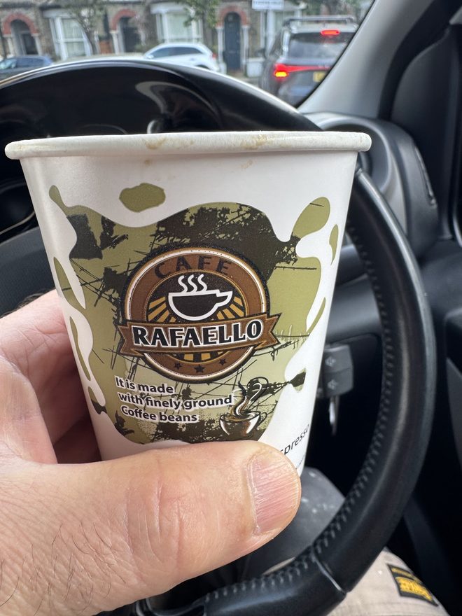 A takeaway coffee held in hand on the way out